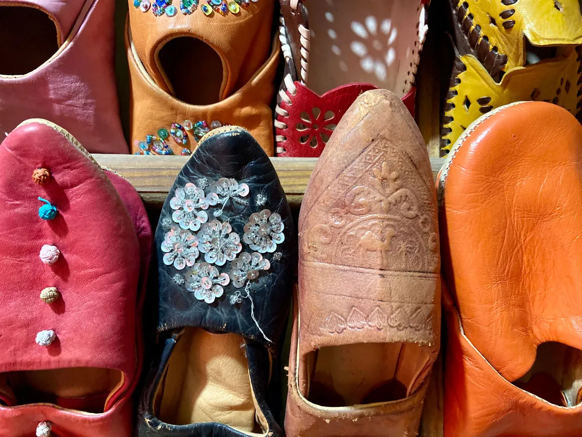 Babouches en cuir rose, orange, bordeaux et noir, certaines brodées de sequins, serrées sur un étal