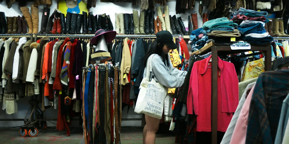Intérieur d’une friperie : portants chargés de vêtements de toutes les couleurs et piles de pulls en hauteur