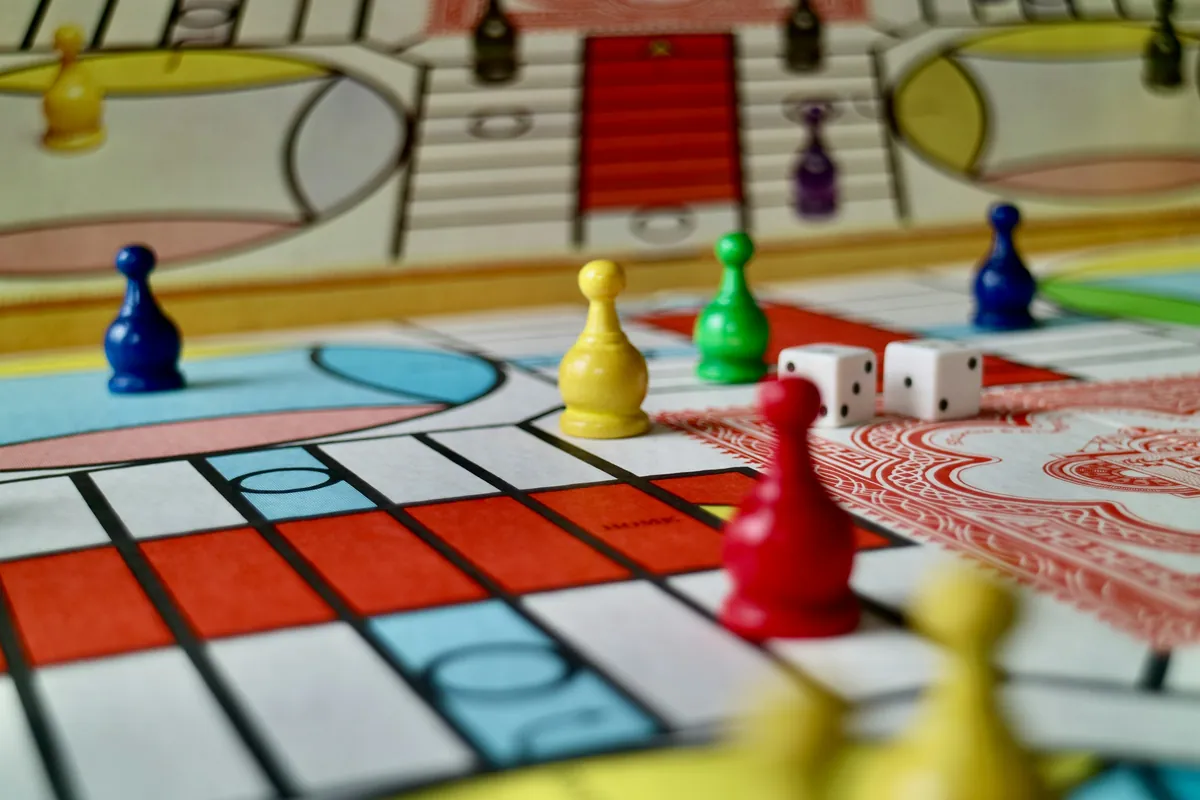 Plateau de jeu de société coloré avec des pions bleus, verts, jaunes et rouges et deux dés blancs