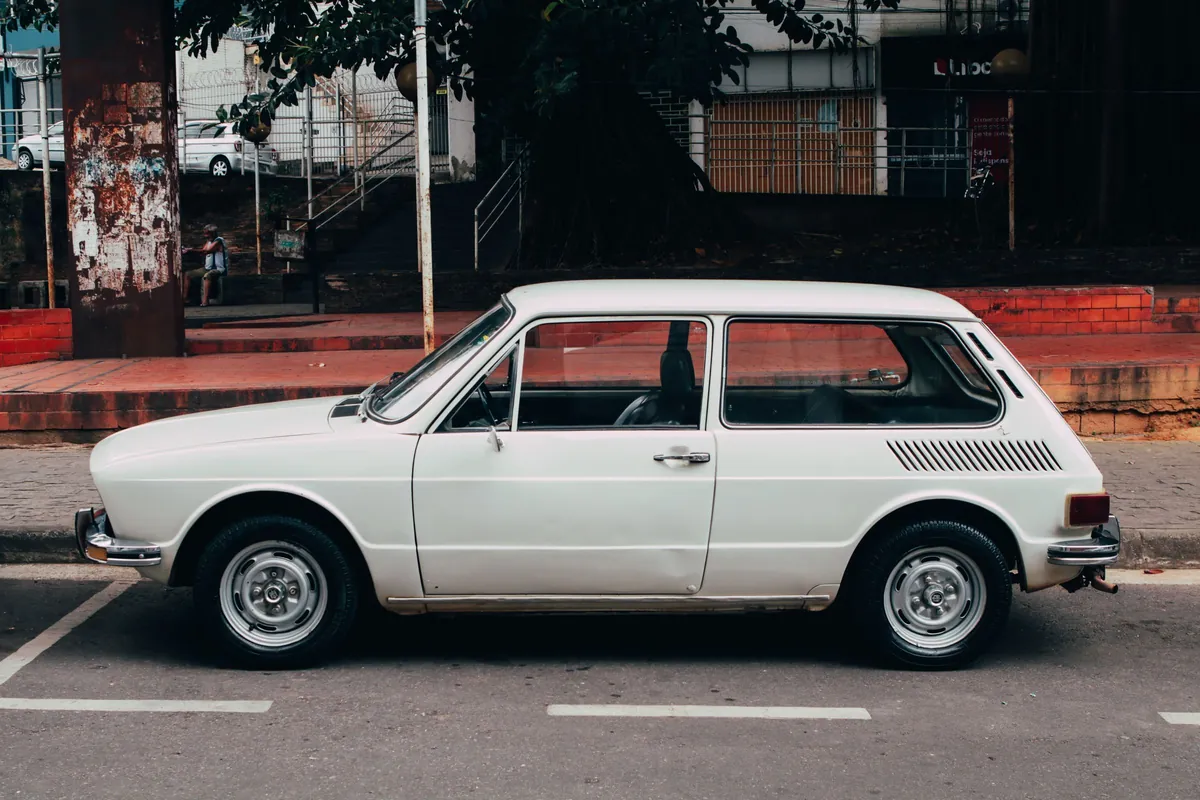 Petite voiture break blanche des années 1970 vue de profil, garée dans une rue